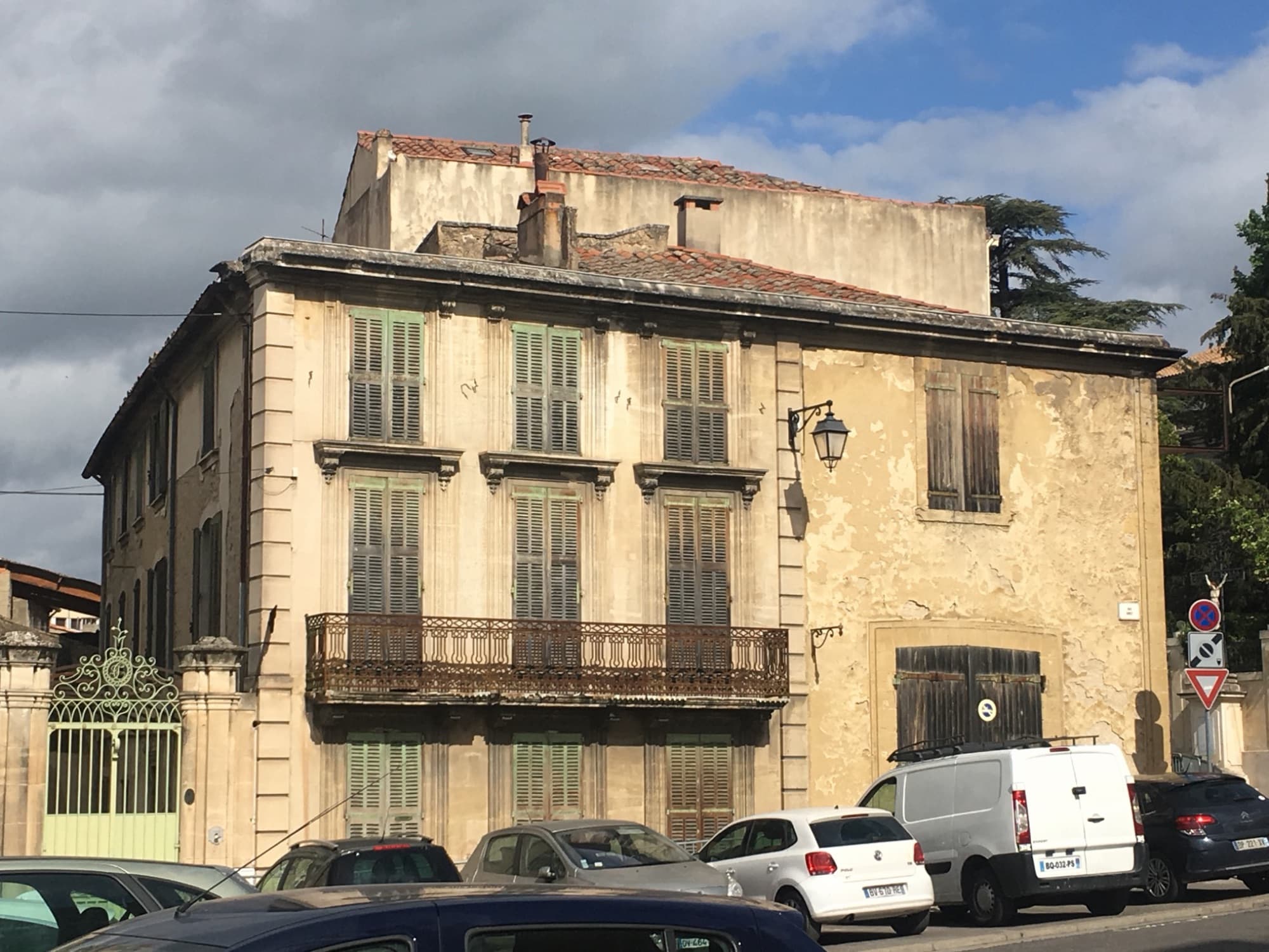 Maison de maître ravalée : façade en pierre claire, volets et balcon en fer forgé verts