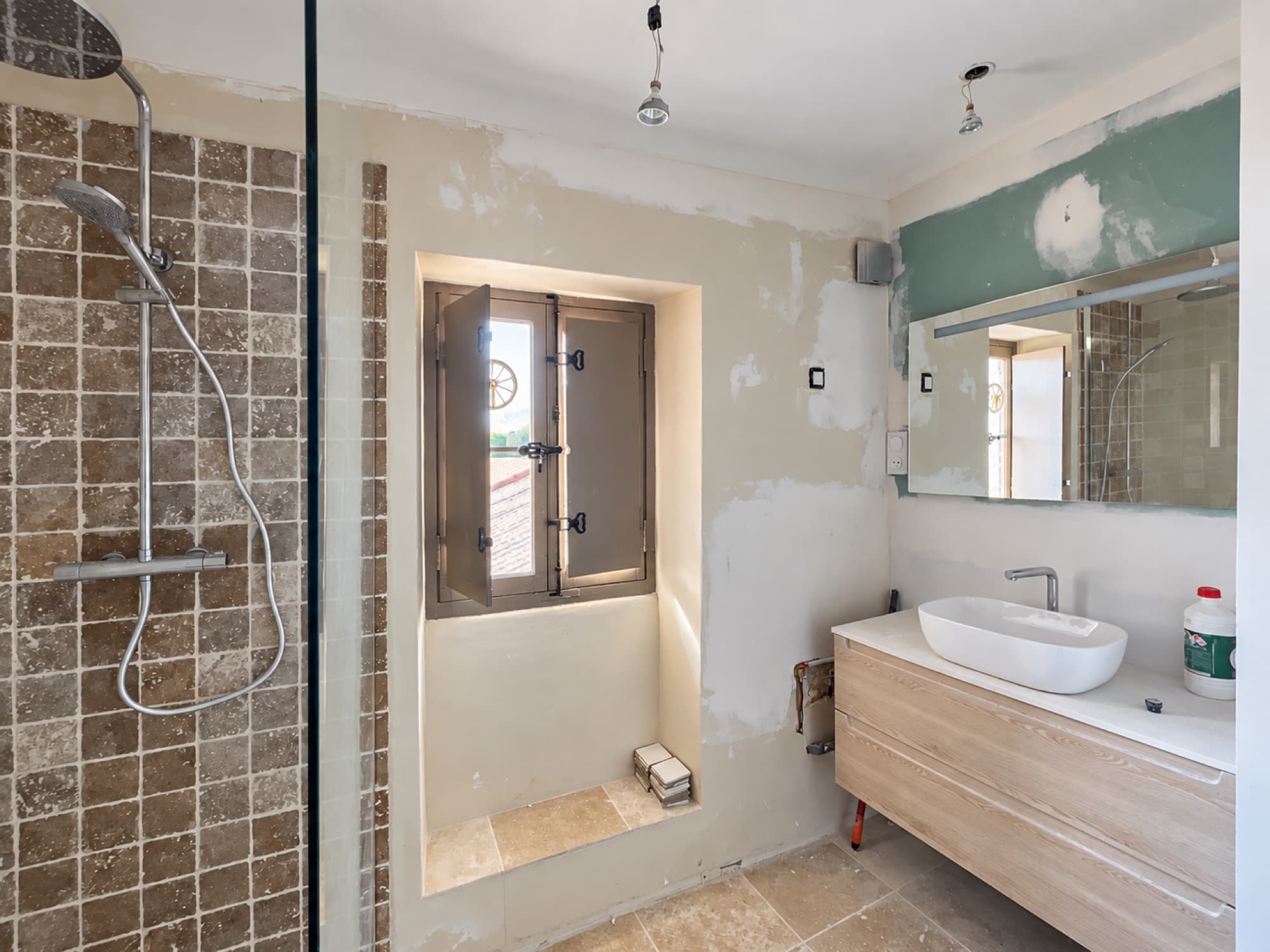 Salle de bains en cours de finition : douche carrelée et meuble vasque posés