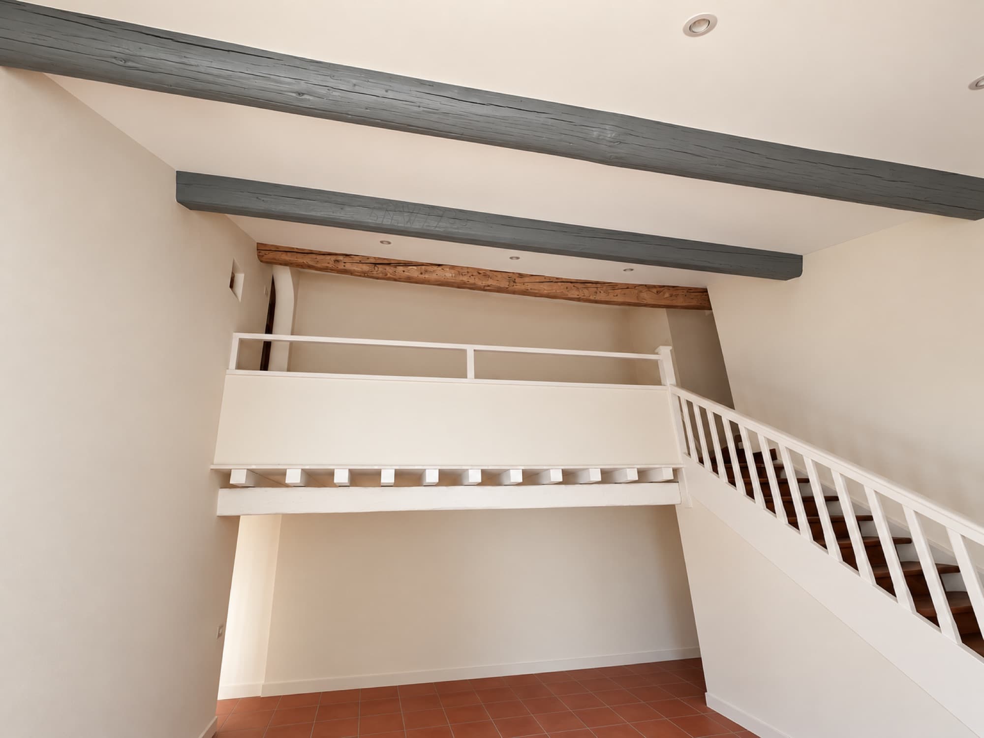 Mezzanine rénovée blanche sous les poutres grises