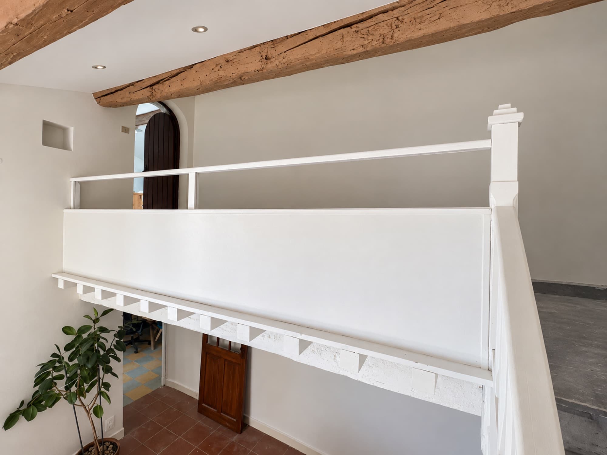 Garde-corps de la mezzanine peint en blanc sous une poutre ancienne