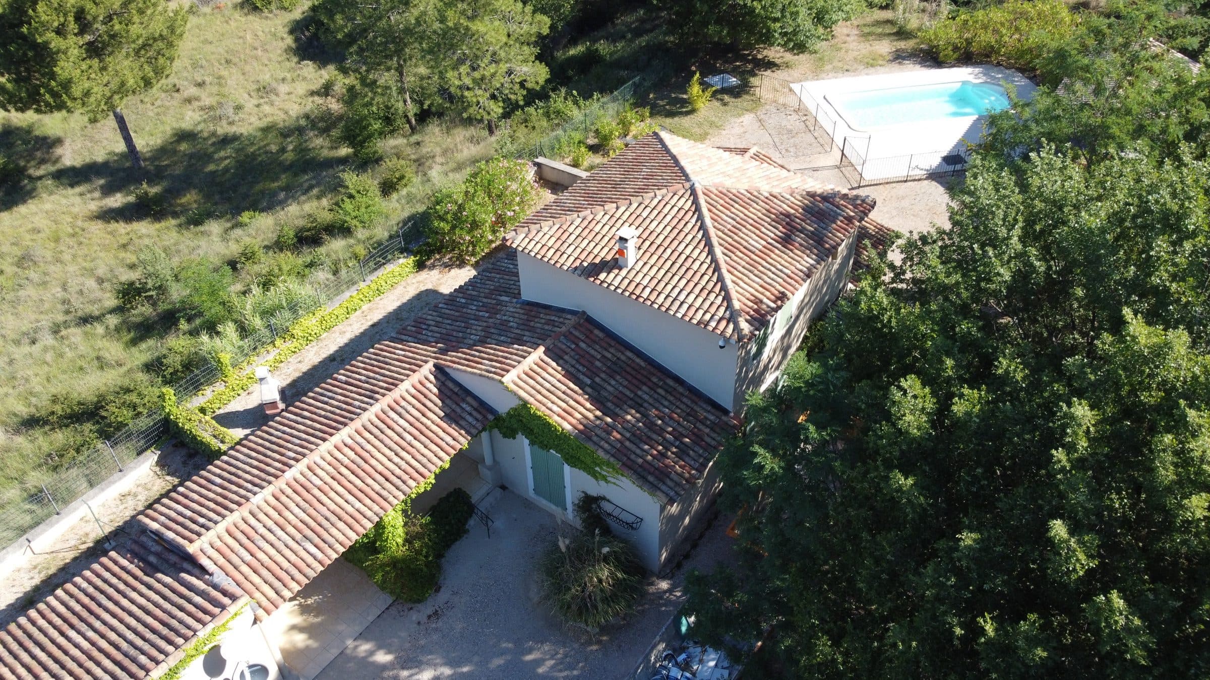 Maison provençale vue du ciel, toits en tuiles et piscine dans les pins