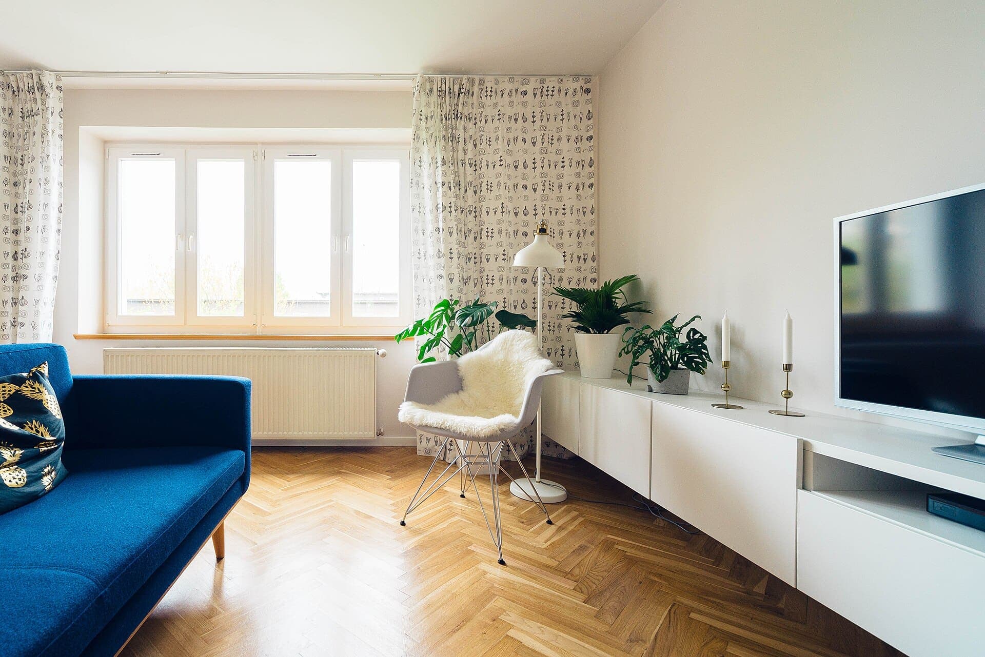 Séjour lumineux, parquet chêne en point de Hongrie, canapé bleu et plantes devant la fenêtre