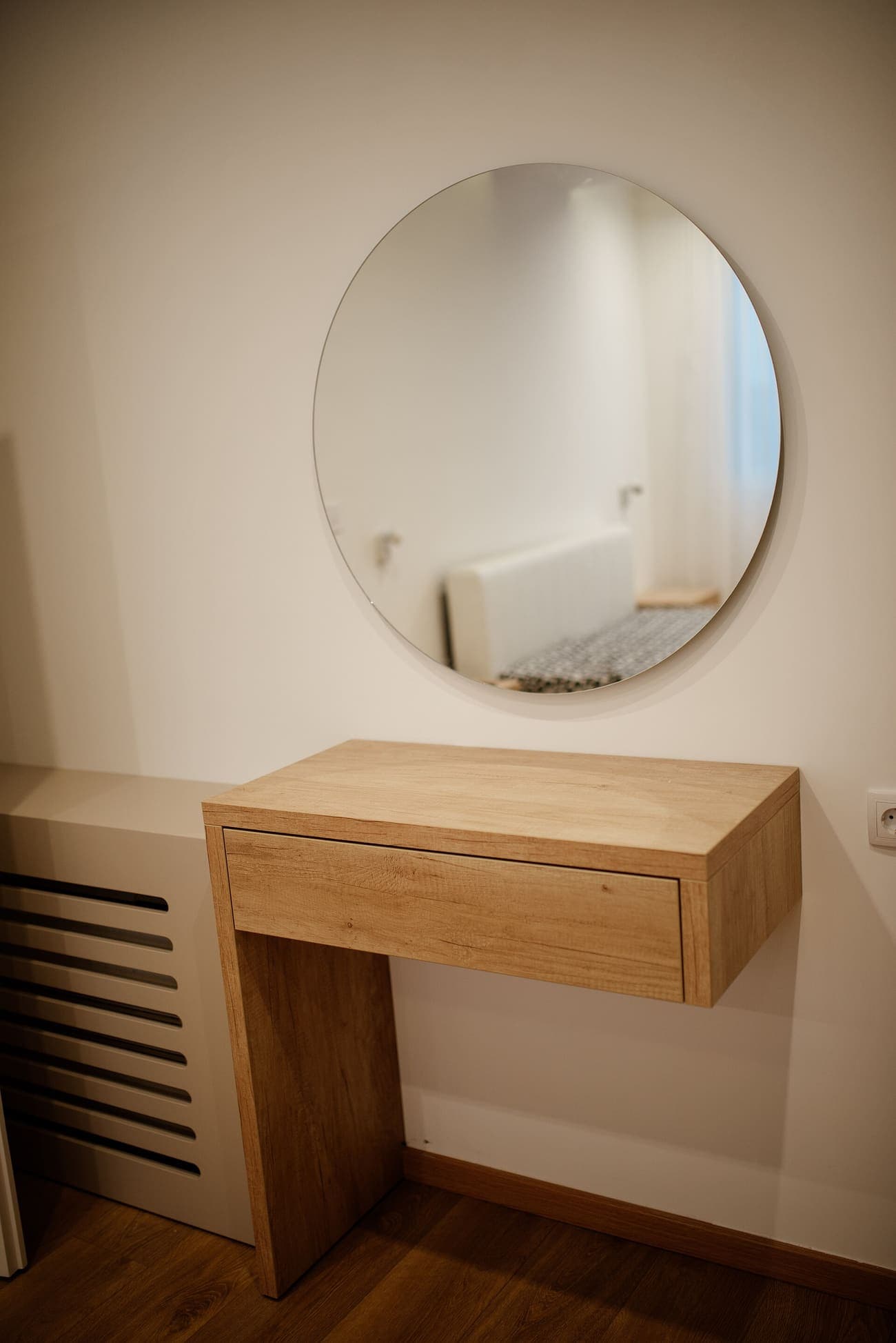 Salle de bains : meuble vasque en chêne clair sous un grand miroir rond